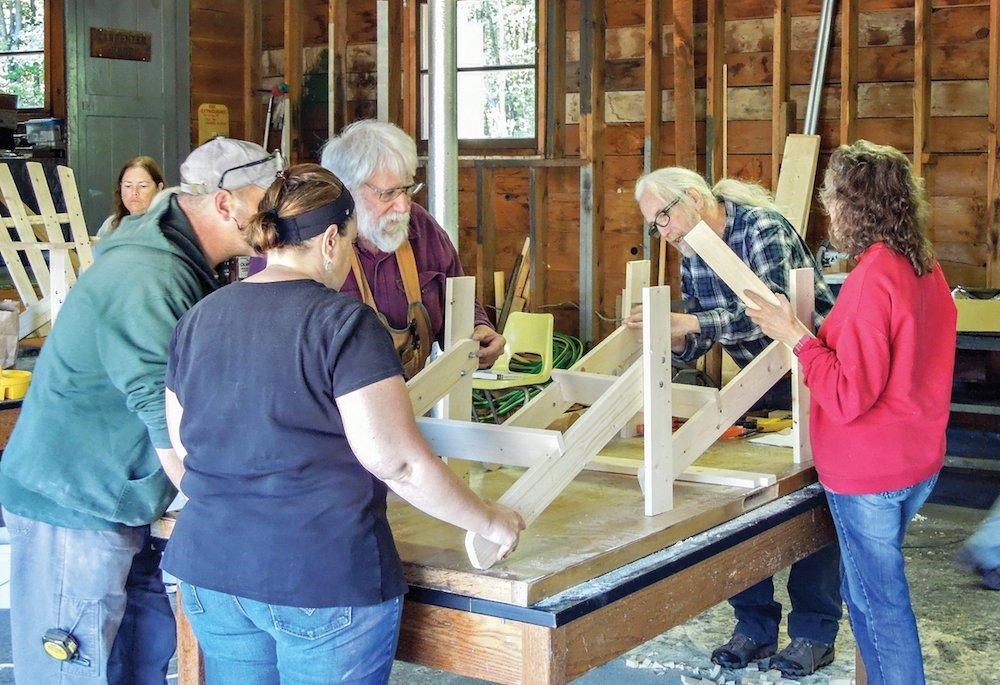 group of 5 people building something out of wood.